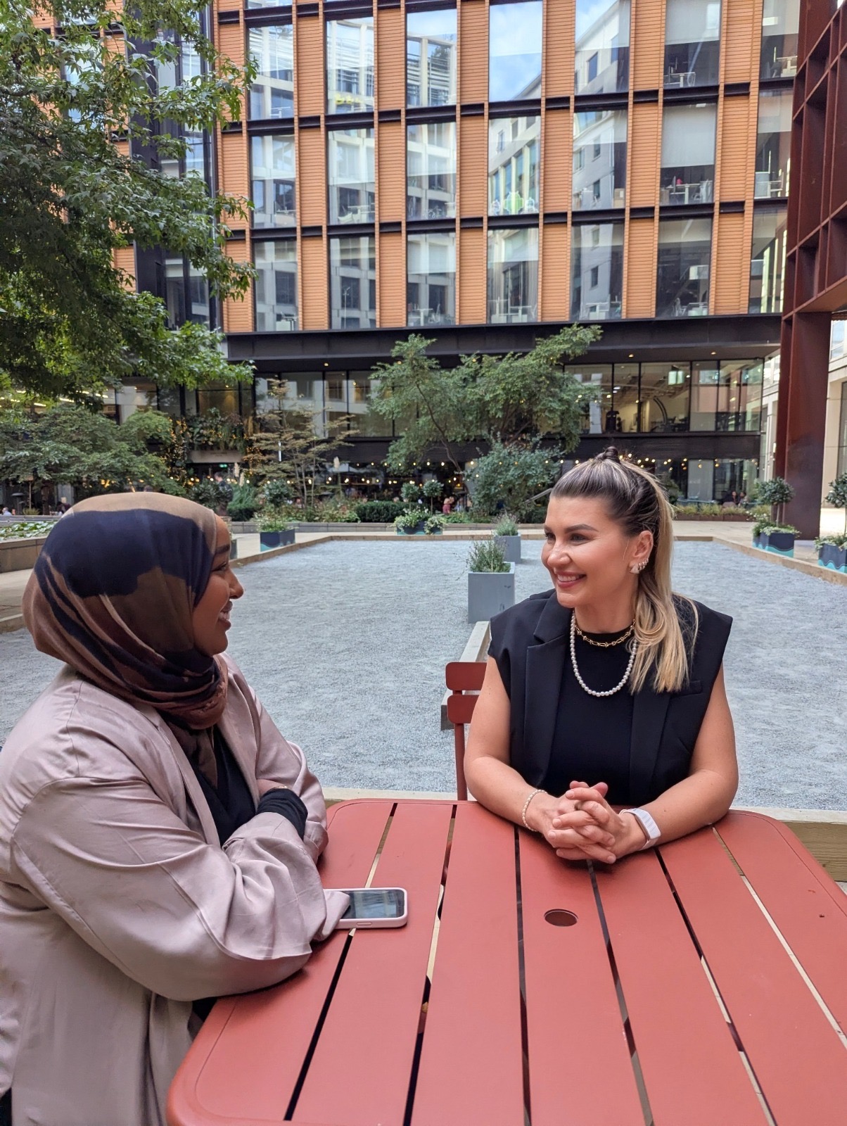 CorpWell founders Ayan Obseyeh and Adriana Pietowska in conversation at an outdoor table