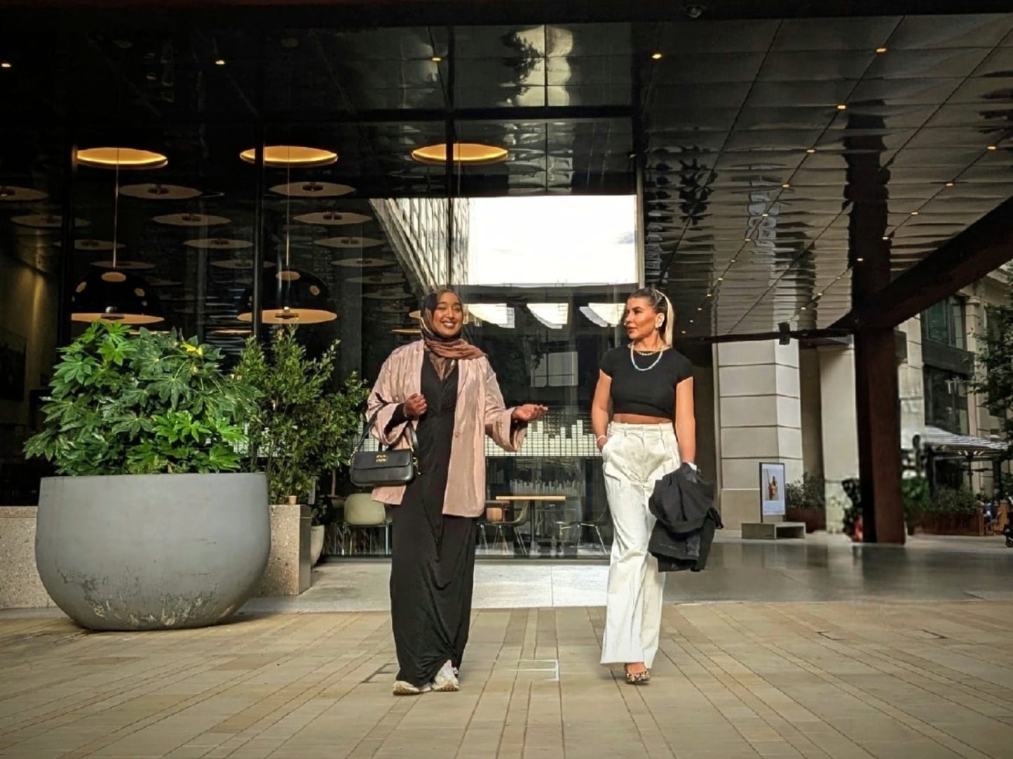 Ayan and Adriana walking together outside a modern building